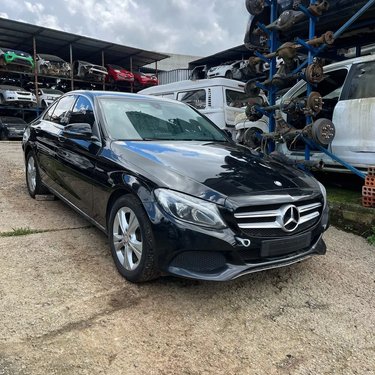 Sedan preto no pátio, com estoque de peças ao fundo